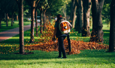 A woman operating a heavy duty leaf blower.